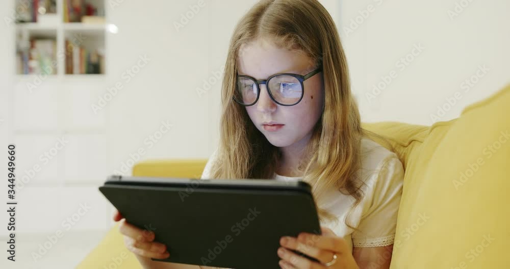 Girl in glasses playing game on tablet Girl in glasses playing game on tablet