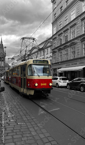 Colored tram driving through black and white streets in Europe