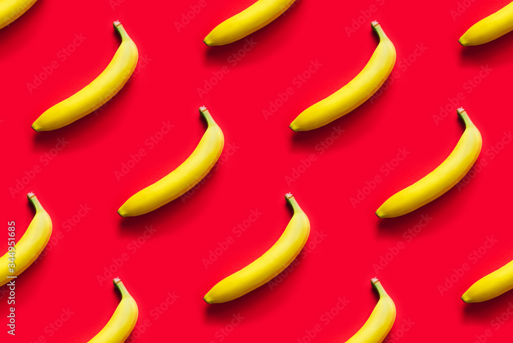Pattern of yellow bananas on a red background. Flat lay.