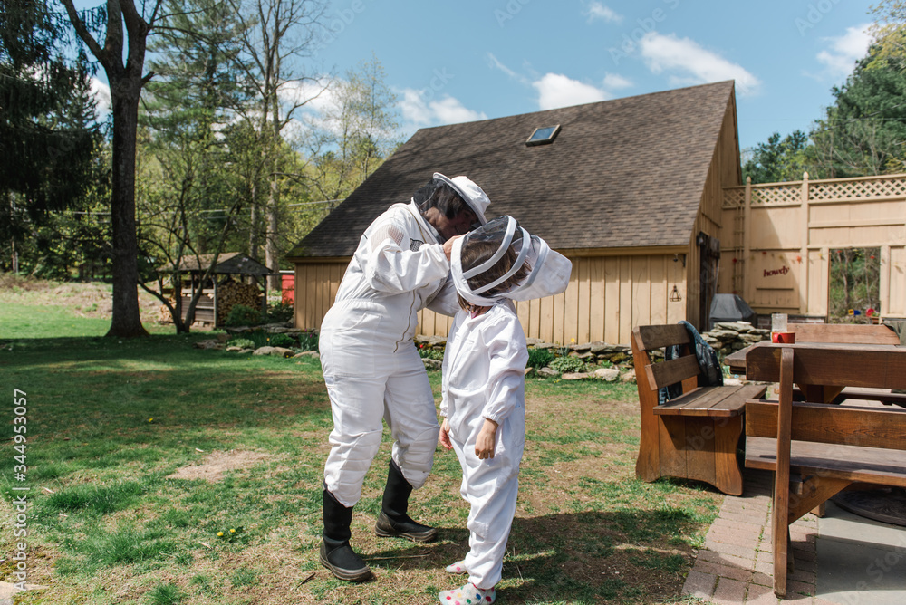 mother helping little girl getting dressed in apiarist suit to check on beehive mother helping little girl getting dressed in apiarist suit to check on beehive