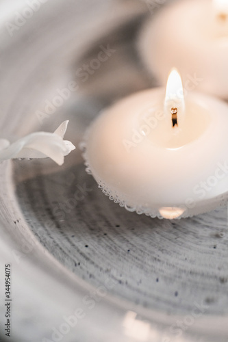Burning candle floating in water close to white petal photo