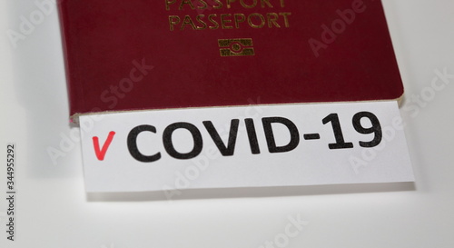 Passport with certificate shows name of disease COVID-19 and red thick sign close up on white background, concept of immunological passport idea
