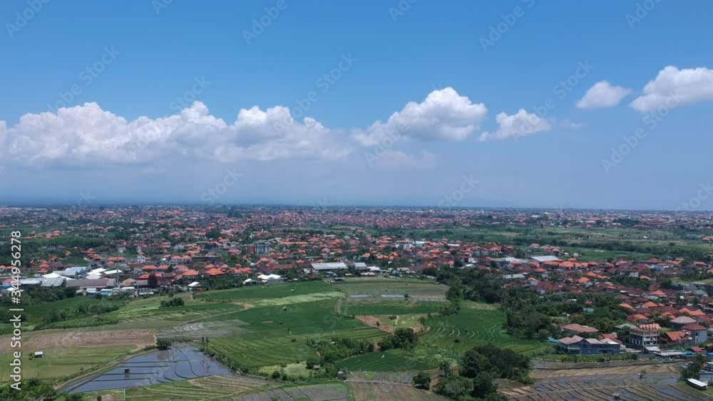 turn on the drone to the right in sunny weather overlooking rice fields and red roofs of houses against the background of the ocean Bali Indonesia turn on the drone to the right in sunny weather overlooking rice fields and red roofs of houses against the background of the ocean Bali Indonesia