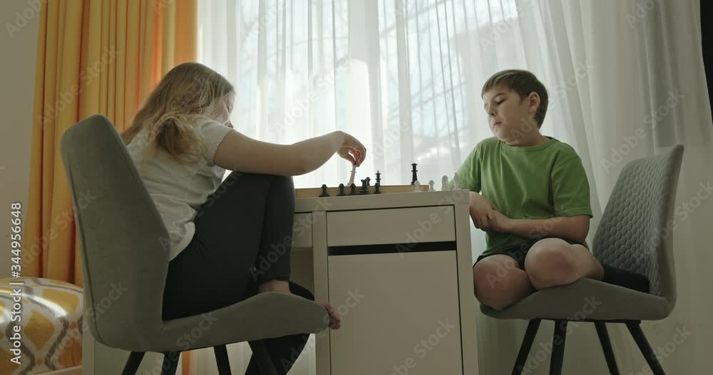 Kids playing chess together near window Kids playing chess together near window