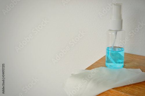 Portable alcohol spray and alcohol gel placed on wood table with white cloth for cleaning point touch such as door,windows etc.Close up. photo