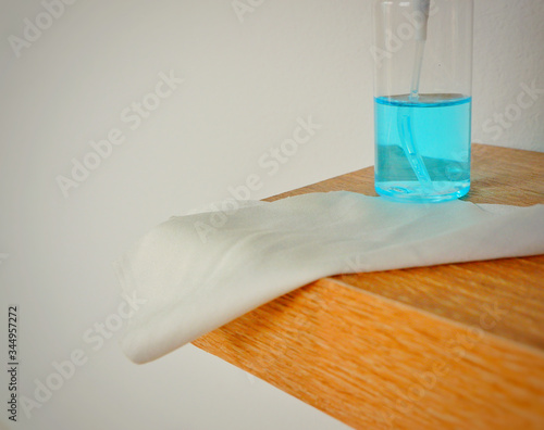 Portable alcohol spray and alcohol gel placed on wood table with white cloth for cleaning point touch such as door,windows etc.Close up. photo