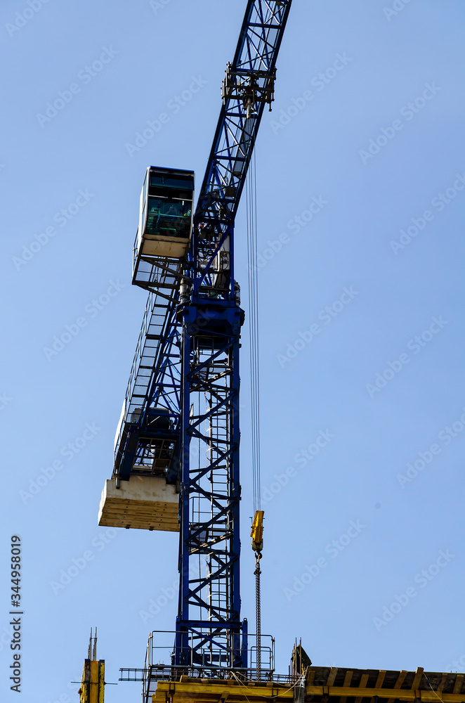 Blue tower crane on a background of clear sky. Vertical format. Blue tower crane on a background of clear sky. Vertical format.
