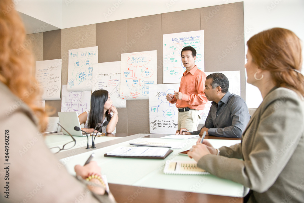 Mature businessman giving presentation to his colleagues in office Mature businessman giving presentation to his colleagues in office