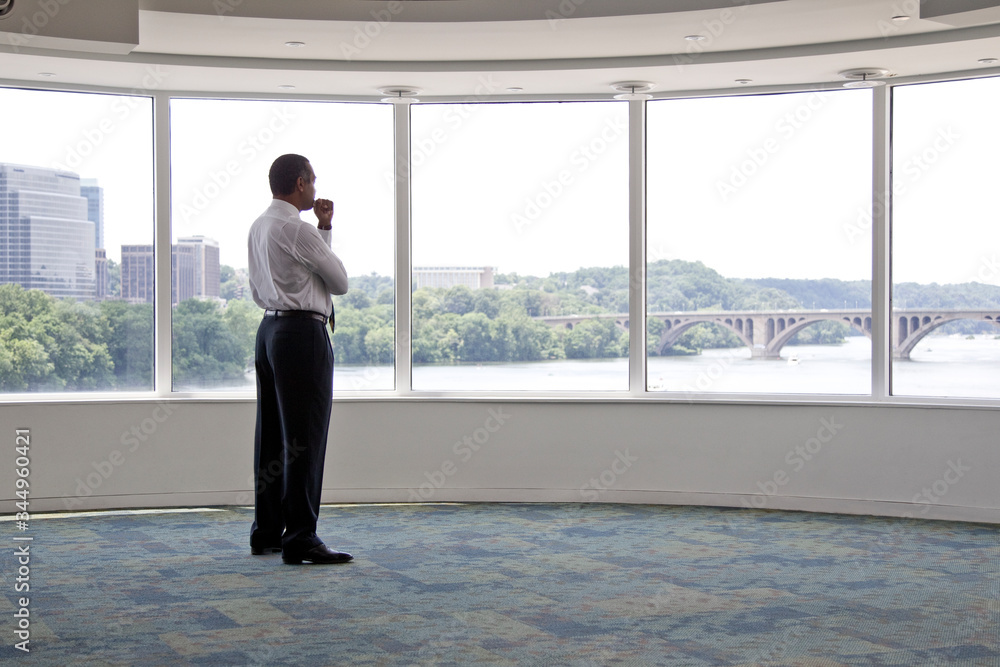 Thoughtful senior businessman looking through window in office Thoughtful senior businessman looking through window in office