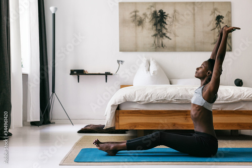 Black Woman Doing Morning Stretching Next to Bed photo