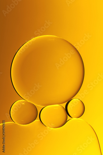 Macro photography of small drops of oil floating on water with yellow background. Abstract composition of great beauty. Background for design.