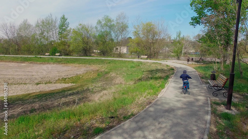 boy riding a blue Bicycle with side wheels along the path in the nature