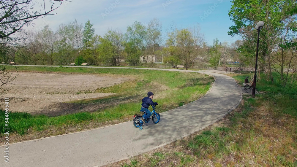 little boy learning to ride a bike with side wheels