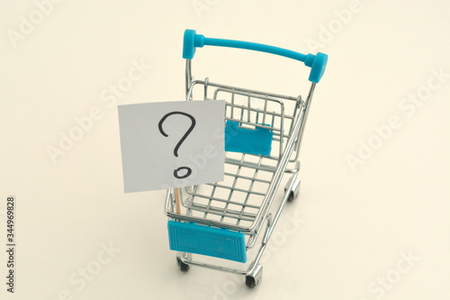 Paper stickers with a question mark in a mini shopping trolley. Concept for solving the problem