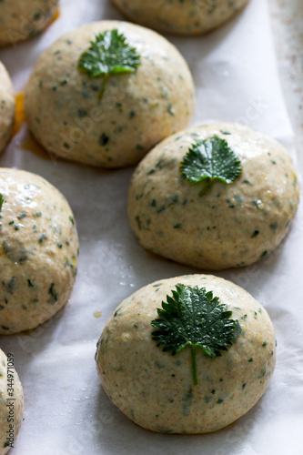 Buns made from yeast dough with nettles, decorated with nettle leaves on an iron pan.