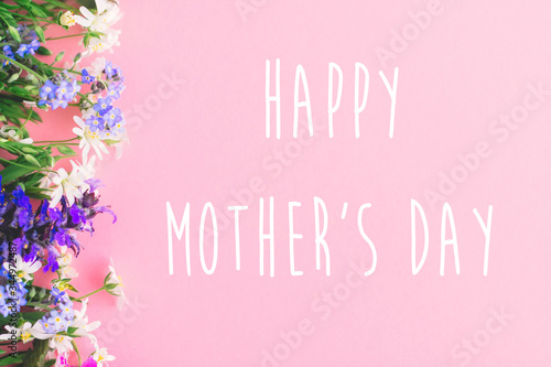 Happy Mother's day text, greeting card. Colorful spring flowers border on pink background flat lay with greeting sign. Floral greeting card. Happy Mothers day concept