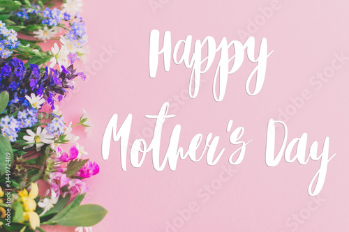 Happy Mother's day text on colorful spring flowers bouquet on pink background. Floral greeting card. Happy Mothers day concept.