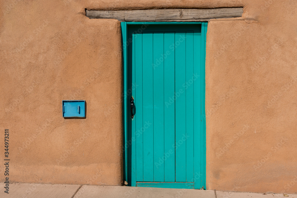 Turquoise Blue Wooden Door with Wood Beam Inset into Southwest Style Adobe Earthen Wall Building Turquoise Blue Wooden Door with Wood Beam Inset into Southwest Style Adobe Earthen Wall Building