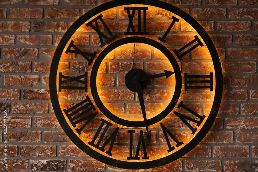 Close up old vintage retro style metal wall clock over background of grunge brick wall - loft style