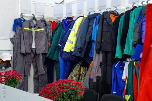 Wide view of wear clothes, dresses, skirts, trousers, jackets, shoes with shelves, racks and hangers inside fashion retail store in large mall.