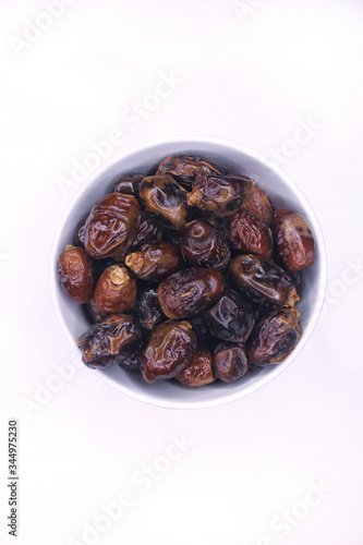 Semi dried date fruit in white bowl close up top view