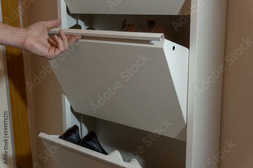 A man taking his shoes off a layered mechanical shoe cabinet - close up