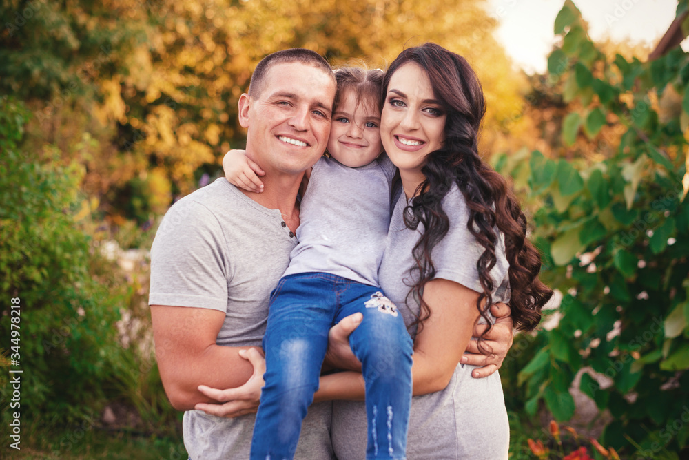 Fototapeta premium Happy young family of mother, father and daughter spending time together outside in green nature.