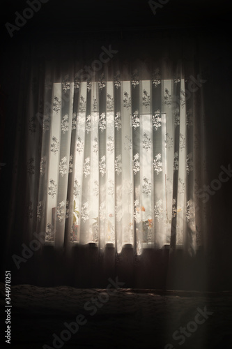 The morning light beats through the window  it seeps through the room flowers accentuates the texture of the curtain