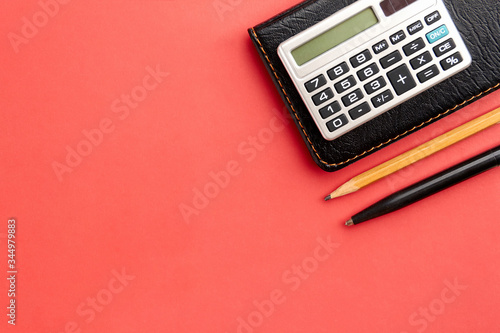Pen, pencil, notebook and calculator on a red background with copy space on the left side. Concept of educational activity and business