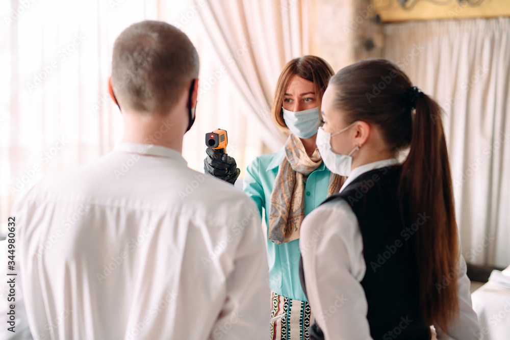 Fototapeta premium The Manager of a restaurant or hotel checks the body temperature of the staff with a thermal imaging device.