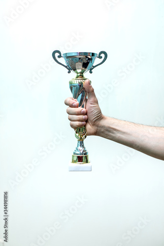 Obraz na płótnie the male hand of the athlete holds the winner's Cup in the competition on a whit