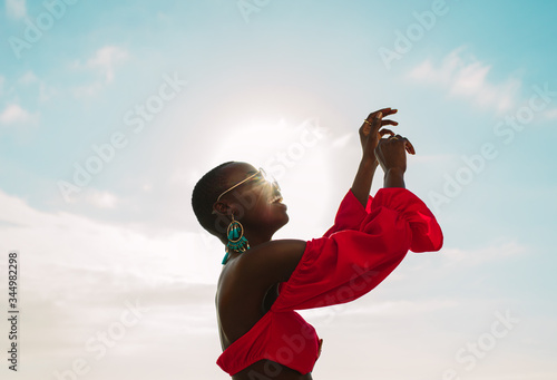 Woman in red dress dancing outdoors on a sunny day