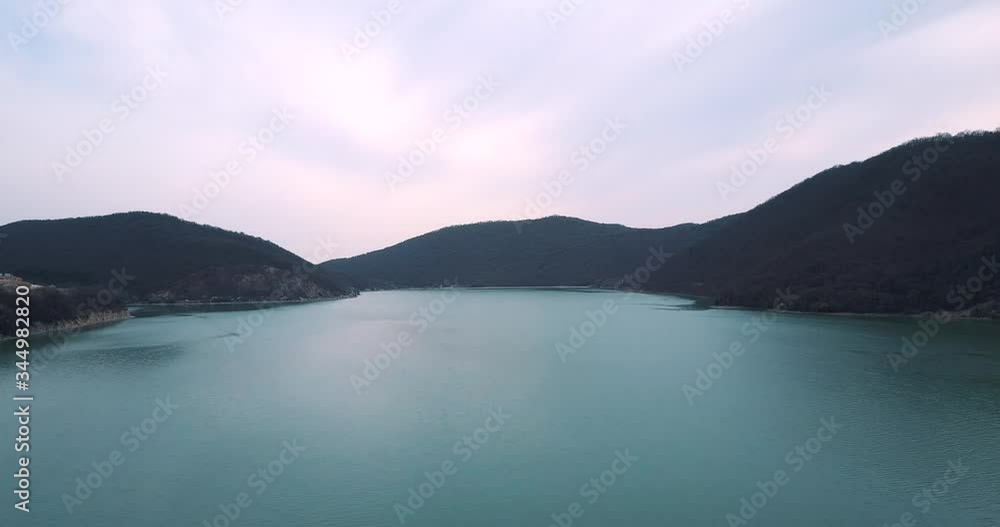 Aerial shoot on a drone of a mountain blue lake with mountains and forest around in cloudy weather Aerial shoot on a drone of a mountain blue lake with mountains and forest around in cloudy weather