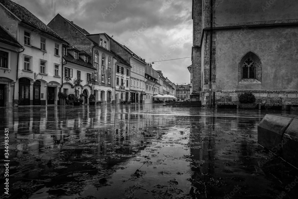 Old town in rainy day in fall season. Empty streets, reflection of building. Black and photo, low angle. Melancholic view of Kranj, Slovenia.