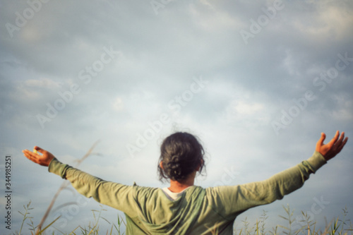 Fotografija Happy young woman with arms outstretched against blue sky background