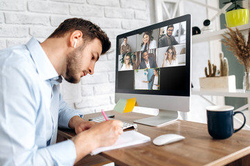 Online training. Young guy learns online by video conference in zoom app. On the screen, the teacher tells the information to him and other participants in the conference