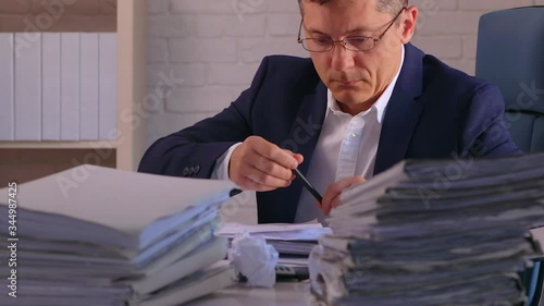 A businessman is overloaded by work with data.