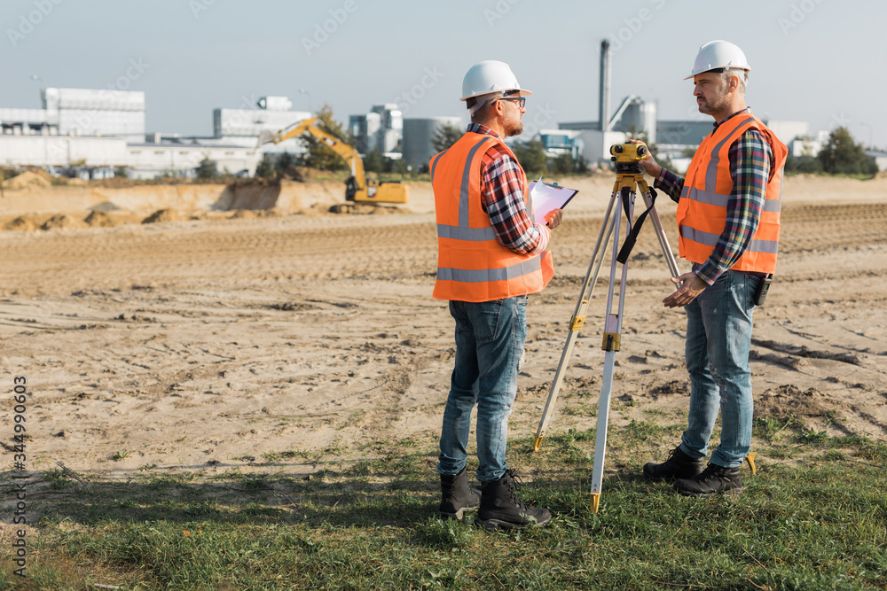 Two road construction workers using measuring device on the field Two road construction workers using measuring device on the field