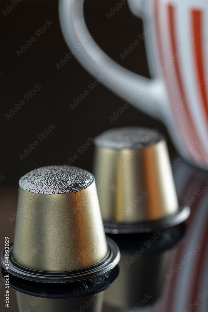 coffee capsules and next to it a cup with reflections