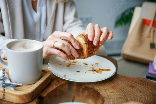 The girl breaks a croissant with her hands