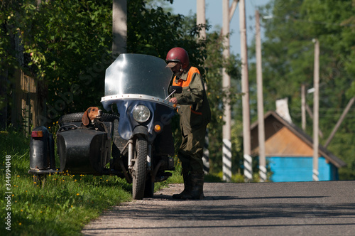 Ostrovets, Grodno region, Republic of Belarus - July 27, 2016: grandfather rides an retro motorcycle with his dog. Illustrative editorial. 