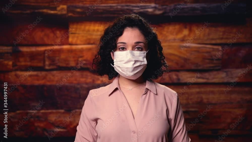 A concerned essential healthcare worker puts on a mask before her shift, worried about what work will bring that day. A concerned essential healthcare worker puts on a mask before her shift, worried about what work will bring that day.