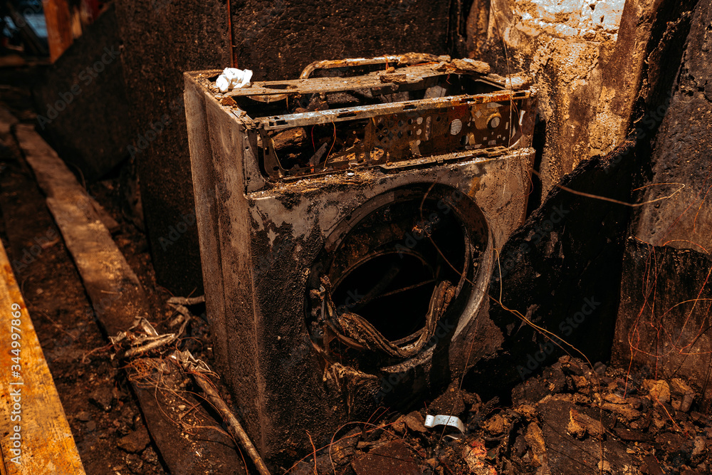 Burnt house interior. Burned bathroom, Fused remains of furniture and washing machine.