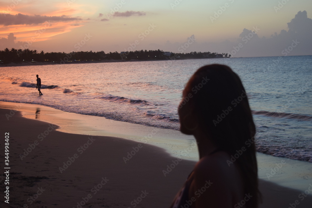 A WOMAN LOOKING AT THE SUNSET AT THE BEACH