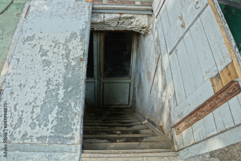 descent to the basement on the street with stone steps and an open shabby old wooden door