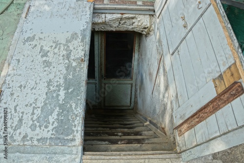 Fototapeta Naklejka Na Ścianę i Meble -  descent to the basement on the street with stone steps and an open shabby old wooden door