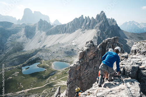 People with climbing gear are descending from the Toblinger Knoten summit, in the Background is the tre cime di lavaredo, Italy