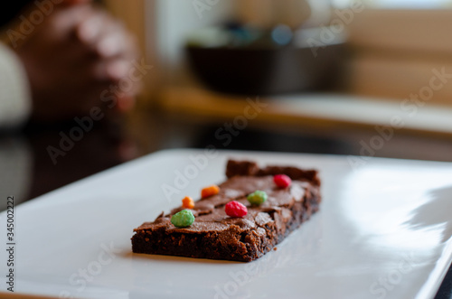 Homemade brownie on white plate. Brownie on black counter. Brownie with decoration. Brownie with smiley.