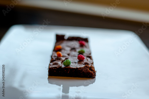 Homemade brownie on white plate. Brownie on black counter. Brownie with decoration. Brownie with smiley.