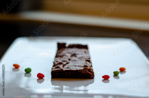 Homemade brownie on white plate. Brownie on black counter. Brownie with decoration. Brownie with smiley.
